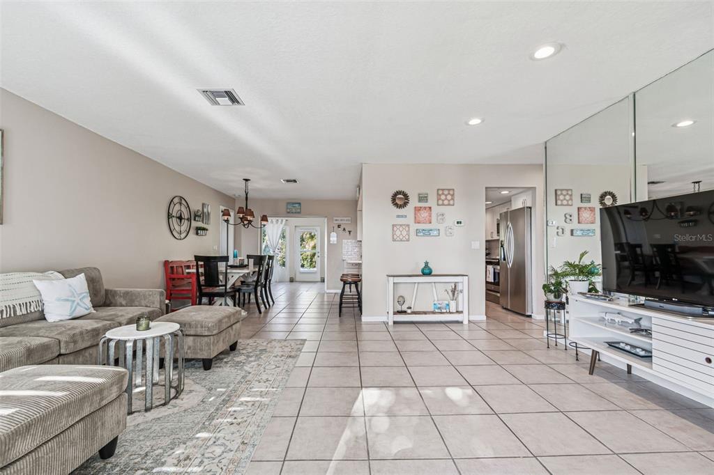 A living room with tile floors, a grey sectional sofa, and a dining area beyond — 216 176TH AVENUE E, REDINGTON SHORES, FL