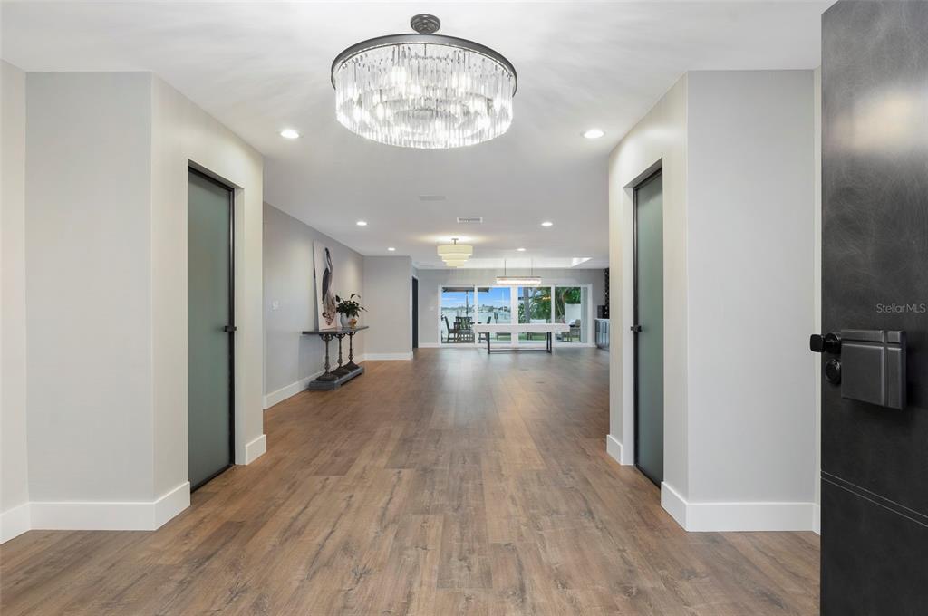A modern kitchen features a large dark island, light grey cabinetry, and a wine rack wall — 303 N BATH CLUB BOULEVARD N, NORTH REDINGTON BEACH, FL