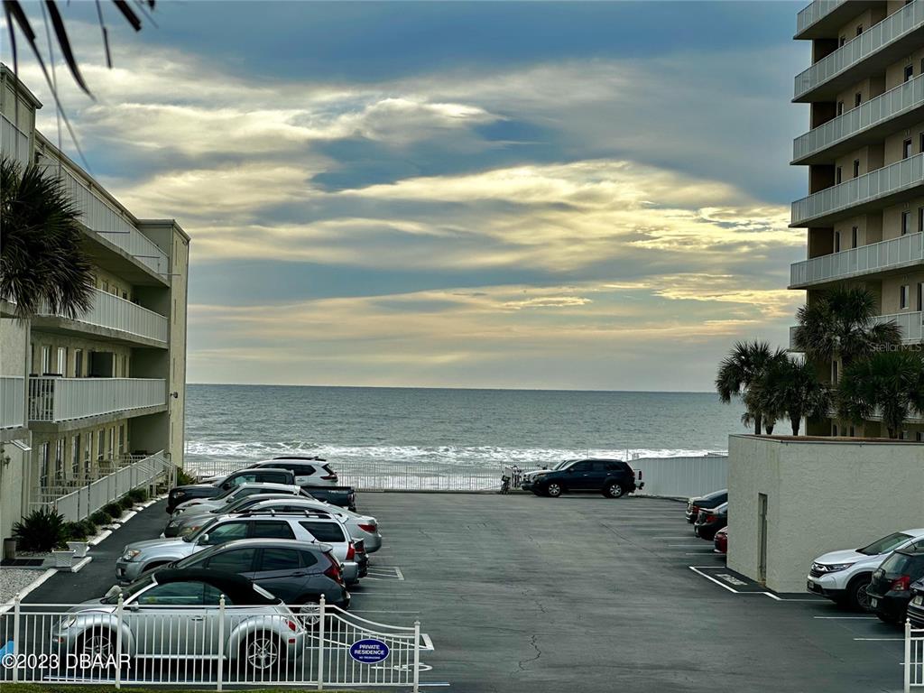 A parking lot sits between two apartment buildings with a view of the ocean — 3733 CARDINAL BOULEVARD UNIT 2, DAYTONA BEACH, FL