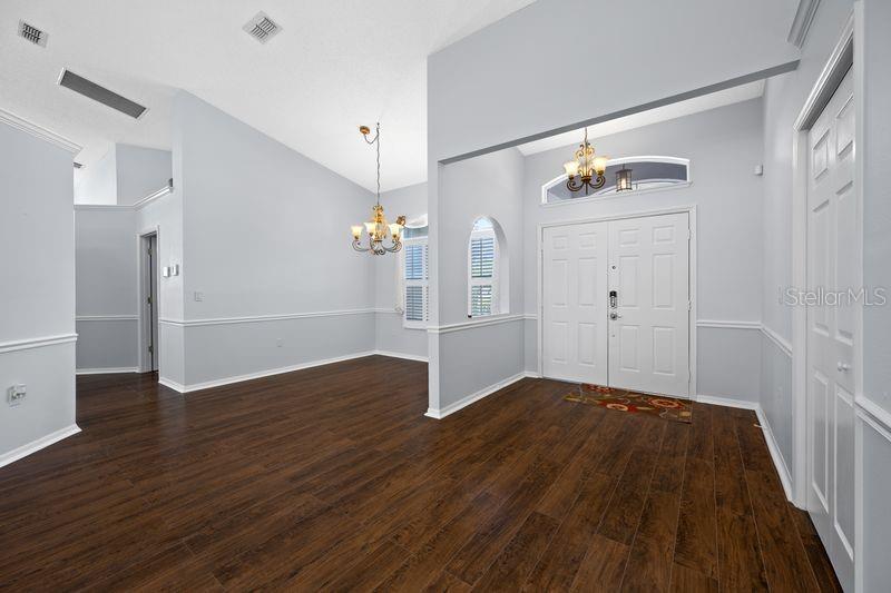 An entryway and dining area with light gray walls, white trim, and dark wood flooring — 5321 GARDENS DR, SARASOTA, FL