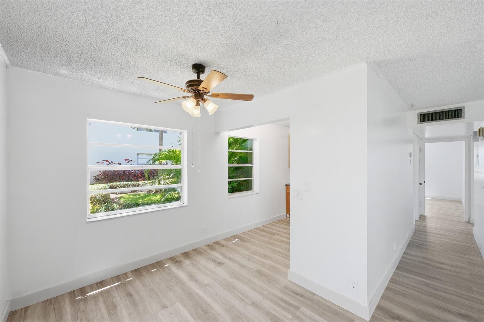 A bright room with white walls, wood-look flooring, a ceiling fan, and two windows — 452 Normandy # J, Delray Beach FL 33484, DELRAY BEACH, FL