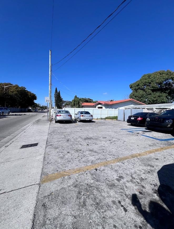 An outdoor parking lot with several parked cars sits beside a white fence and building — 1540 SW 22nd Ave, Miami FL 33145, MIAMI, FL