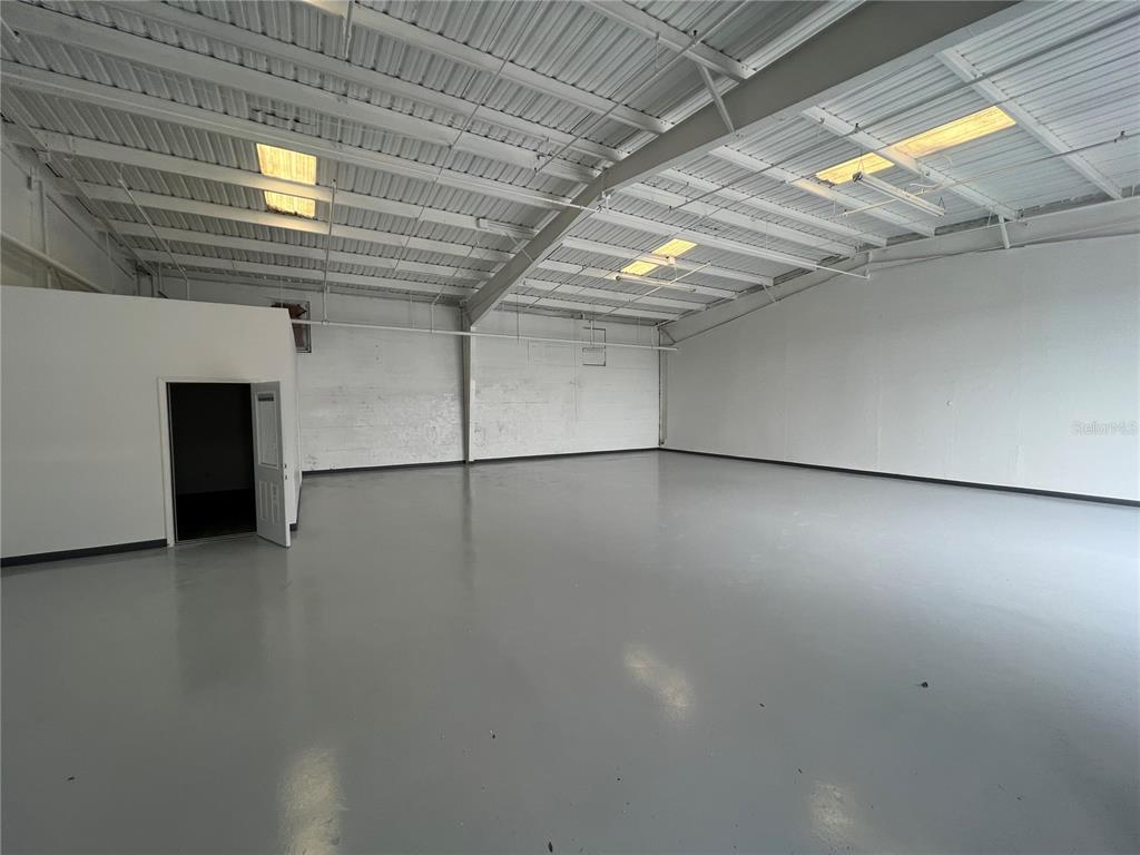 An empty industrial warehouse space features a gray epoxy floor and a high metal ceiling — 5010 N COOLIDGE AVENUE, TAMPA, FL