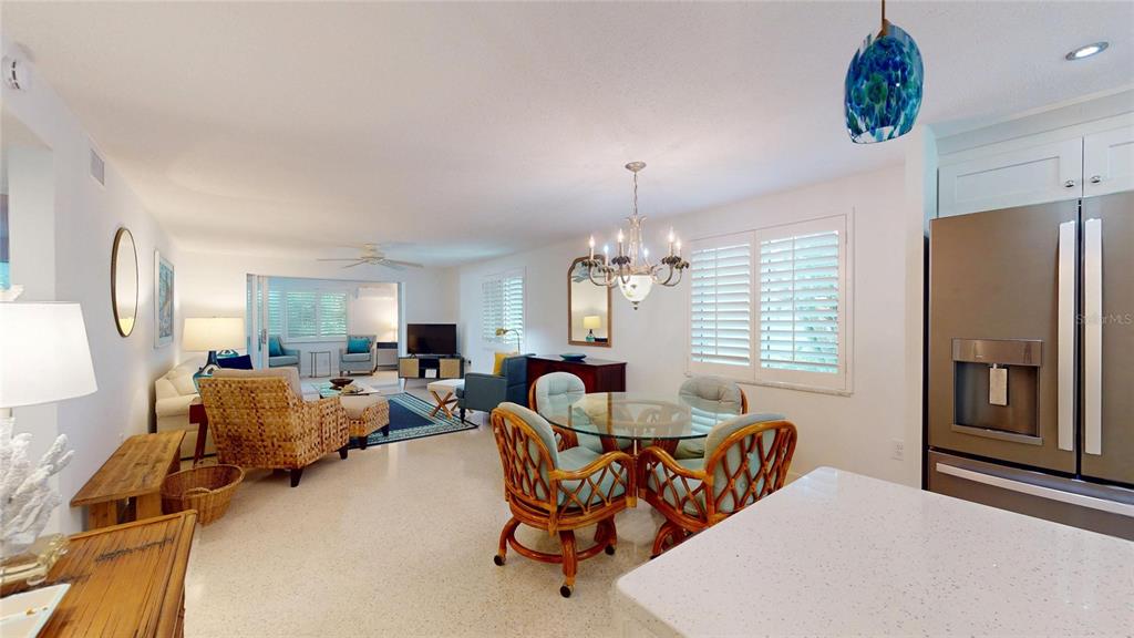 An open-concept living and dining area features tile floors, a glass-topped table, and wicker furniture — 718 SPANISH DRIVE N, LONGBOAT KEY, FL