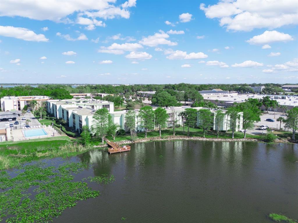 An aerial view shows a multi-story apartment complex situated beside a lake with a dock — 1130 N LAKE PARKER AVENUE UNIT A201, LAKELAND, FL