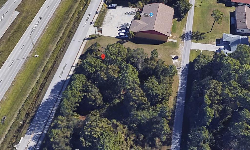 This aerial view shows a wooded lot located between two roads near a commercial building — 3441 S ACCESS ROAD, ENGLEWOOD, FL