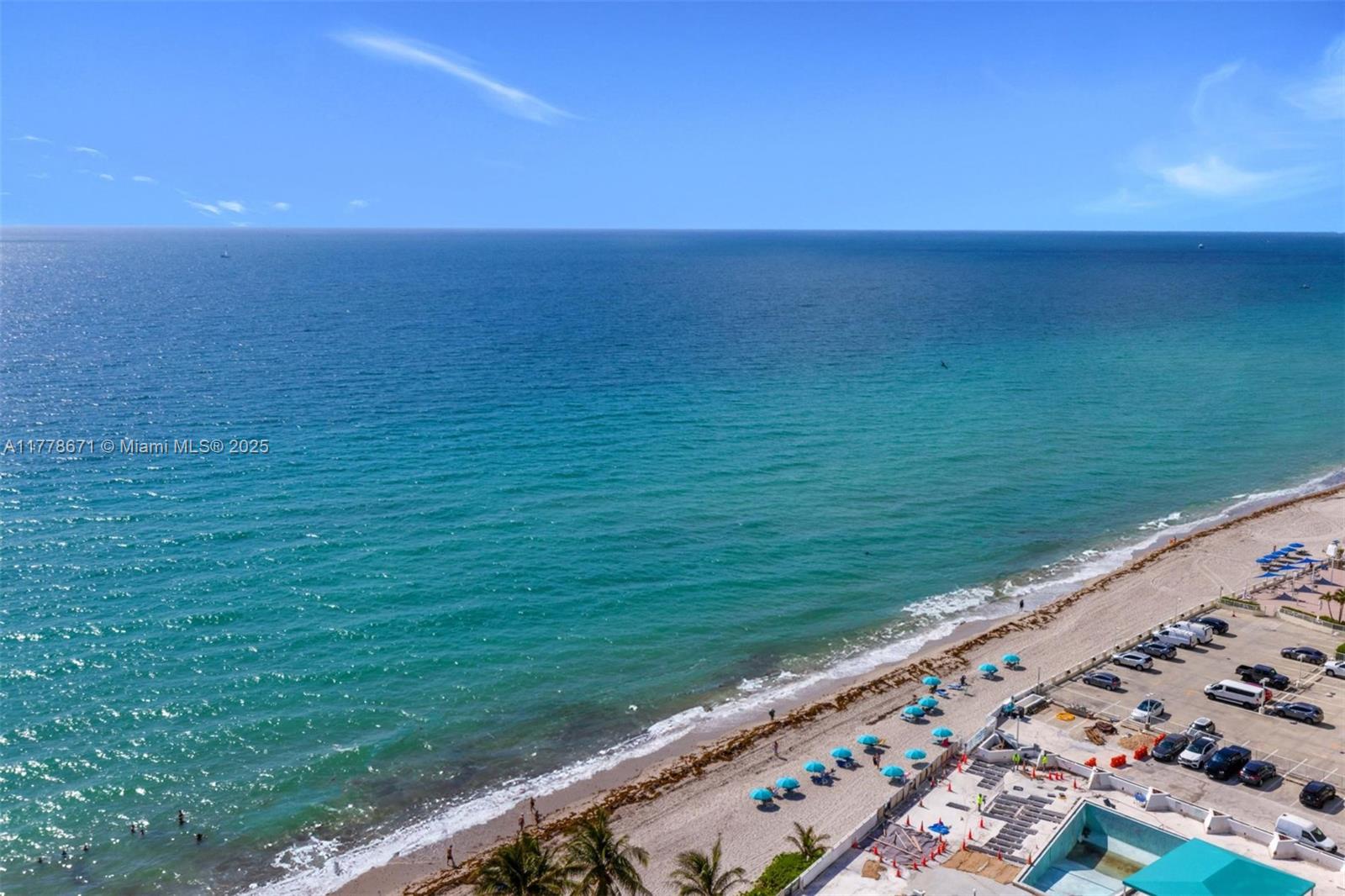 An aerial view shows a sandy beach with blue umbrellas next to a parking lot — 2080 S Ocean Dr, Hallandale Beach FL 33009, HALLANDALE BEACH, FL