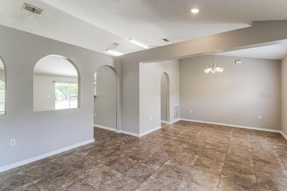 An interior view shows a tiled living area with arched doorways and a vaulted ceiling — 1159 NEWCOMB AVENUE, SPRING HILL, FL