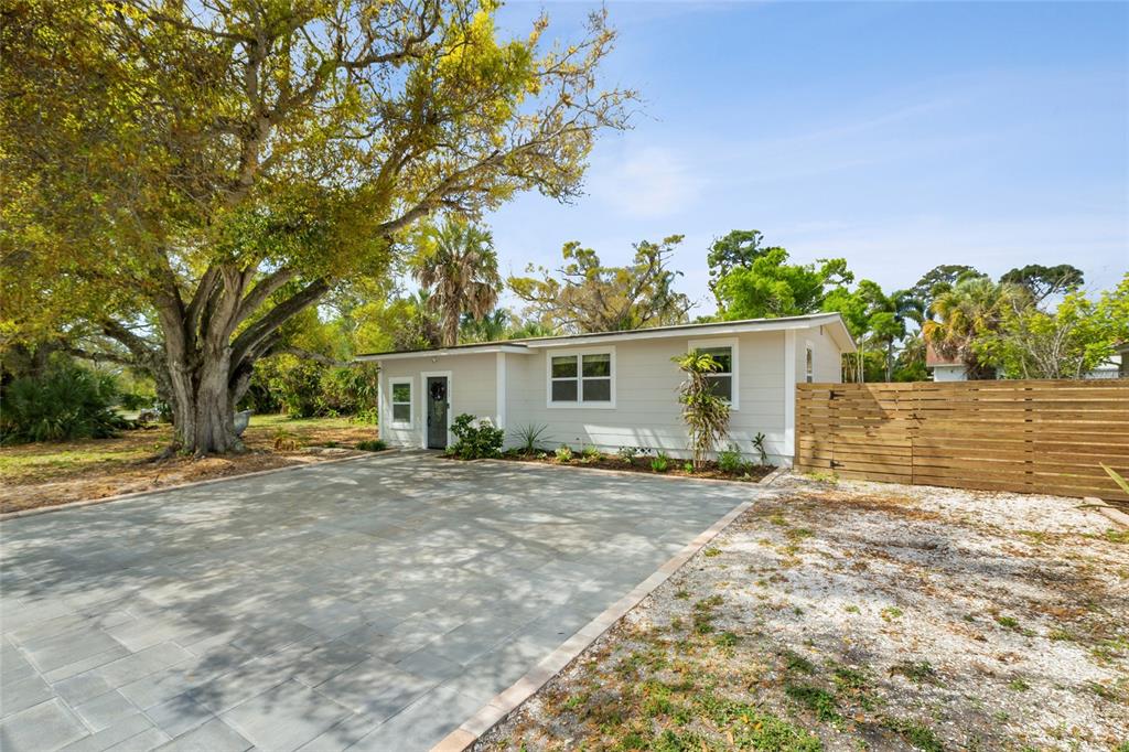 A single-story house with light siding, a paved driveway, and a large tree in front — 5135 OLD BRADENTON ROAD, SARASOTA, FL