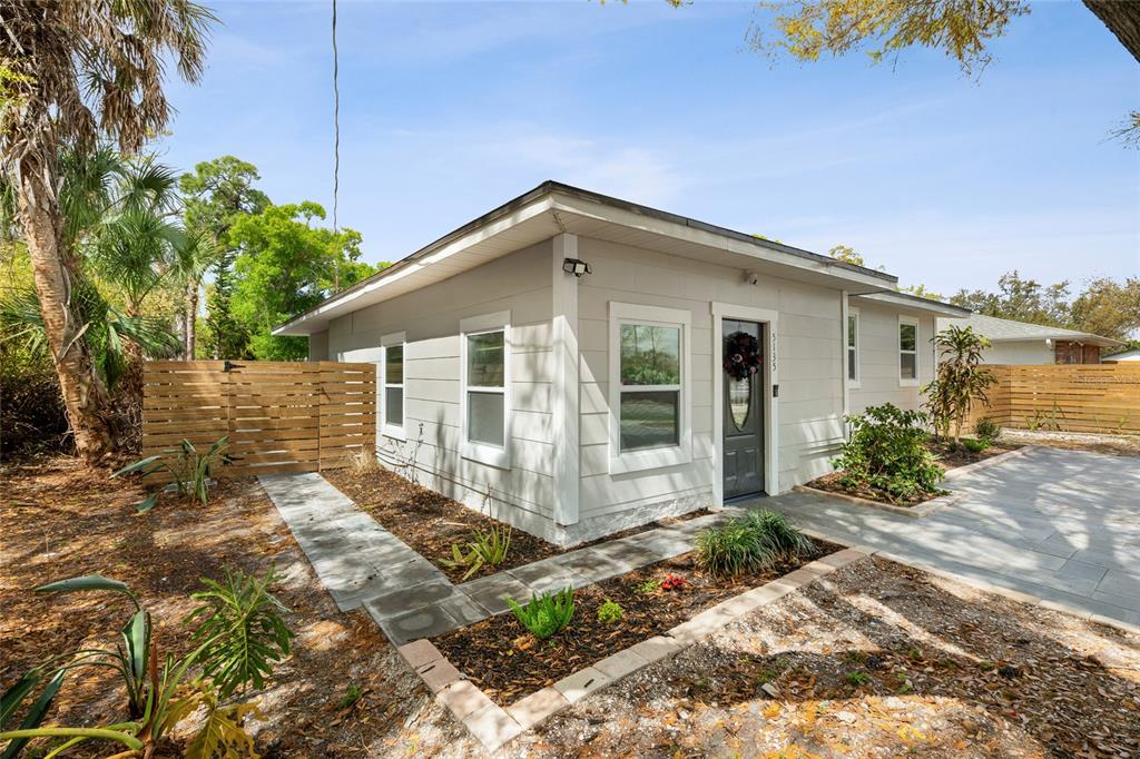 A light gray exterior house features a front door, windows, and a stone walkway — 5135 OLD BRADENTON ROAD, SARASOTA, FL