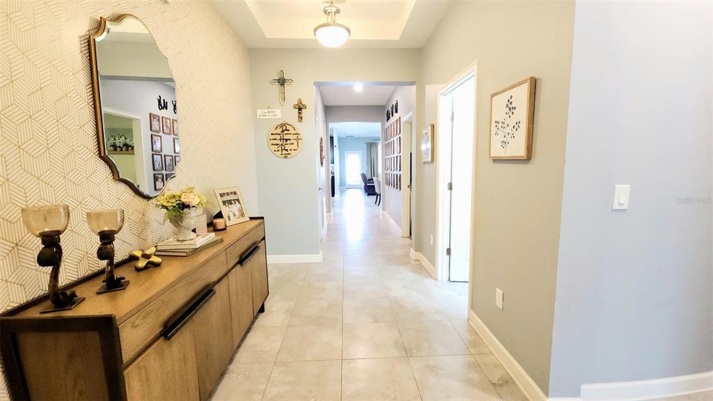 A hallway features tile flooring, a wooden console table, a mirror, and patterned wallpaper — 4687 FAIRY TALE CIRCLE, KISSIMMEE, FL