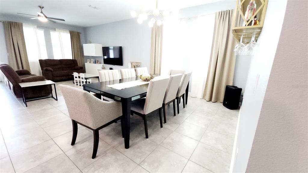 A dining area with a dark table and light chairs sits adjacent to a living room — 4687 FAIRY TALE CIRCLE, KISSIMMEE, FL