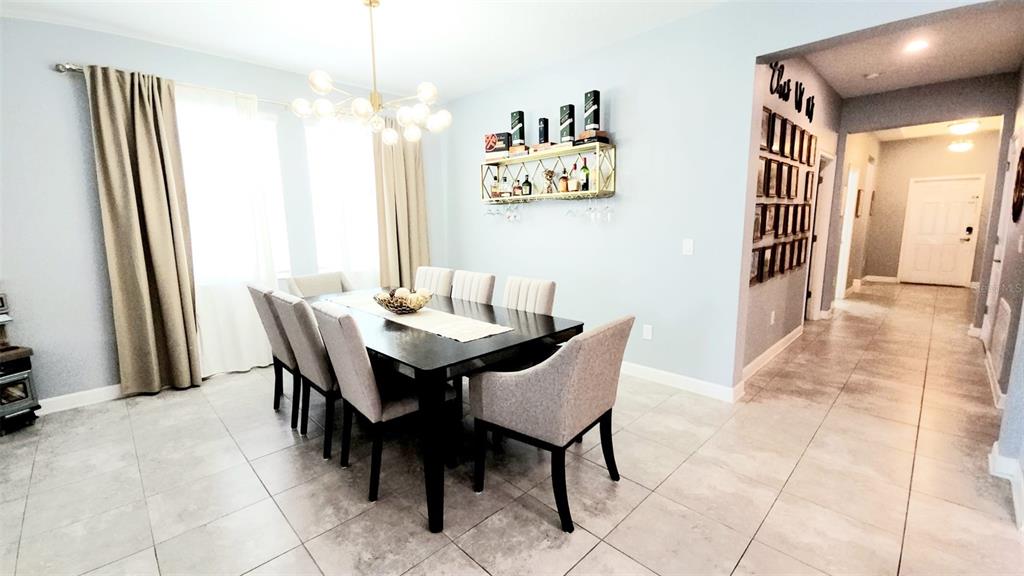 A dining room features a dark wood table, upholstered chairs, a chandelier, and a wall shelf — 4687 FAIRY TALE CIRCLE, KISSIMMEE, FL