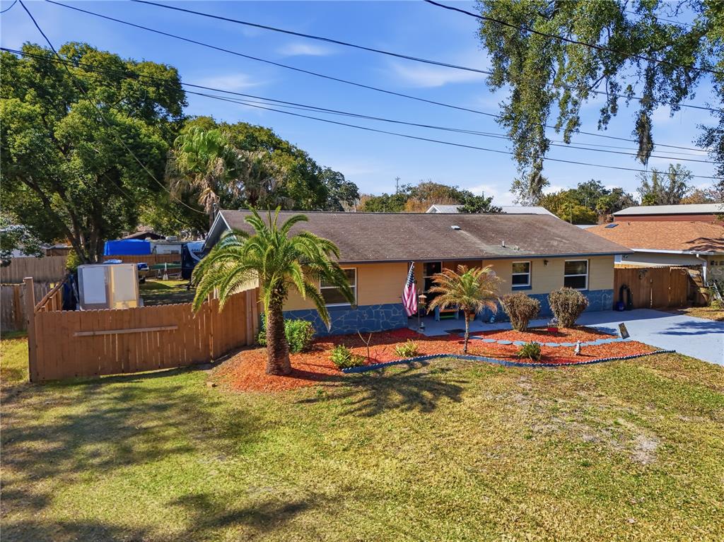 A single-story house with a palm tree in the front yard and a wooden fence — 2670 REAGAN LANE, KISSIMMEE, FL