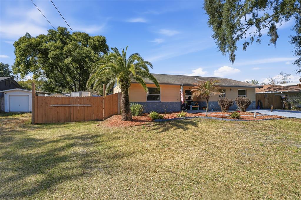 A single-story house with a palm tree, wooden fence, and stone-textured siding exterior — 2670 REAGAN LANE, KISSIMMEE, FL
