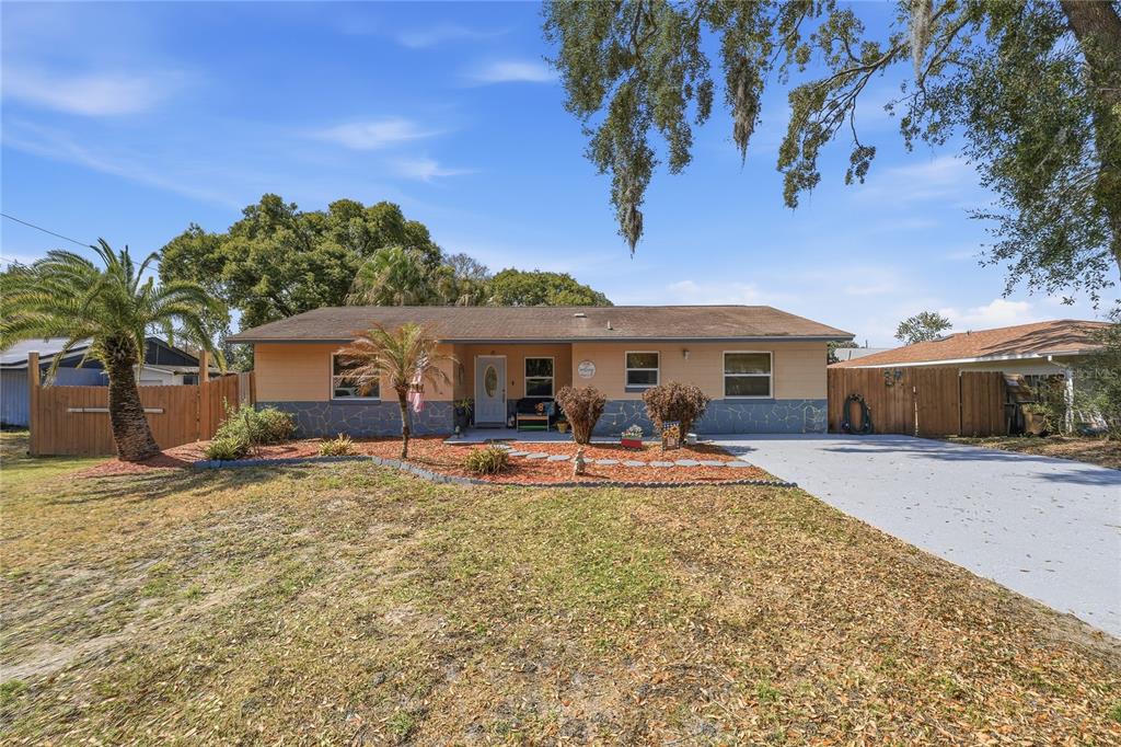 A single-story house with a tan exterior, stone-patterned base, and a paved driveway — 2670 REAGAN LANE, KISSIMMEE, FL