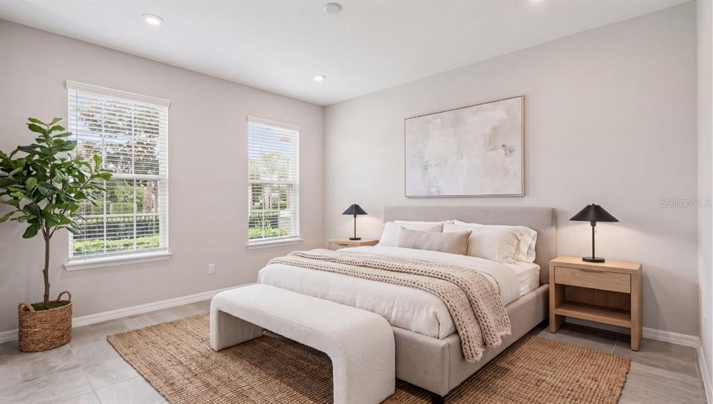 A neutral-toned bedroom features a bed with a bench, two nightstands, and a potted plant — 9457 RANDAL PARK BOULEVARD, ORLANDO, FL