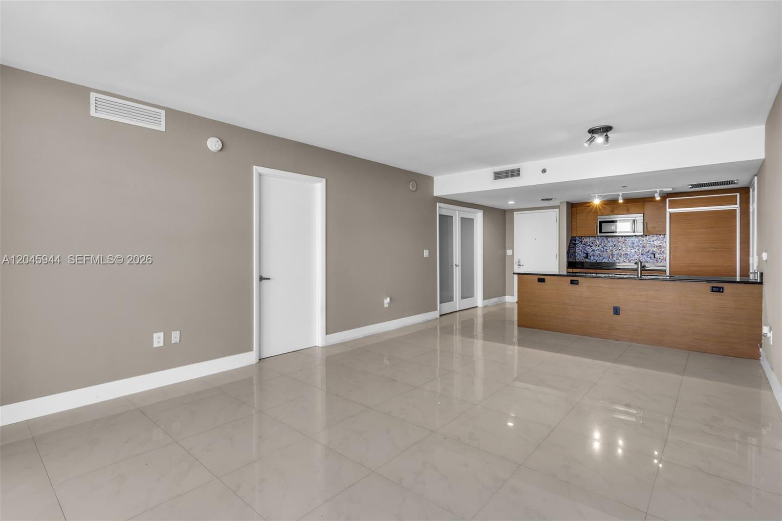An open living area features light-colored tile flooring, a neutral wall color, and a kitchen — 50 Biscayne Blvd # 4208, Miami FL 33132, MIAMI, FL