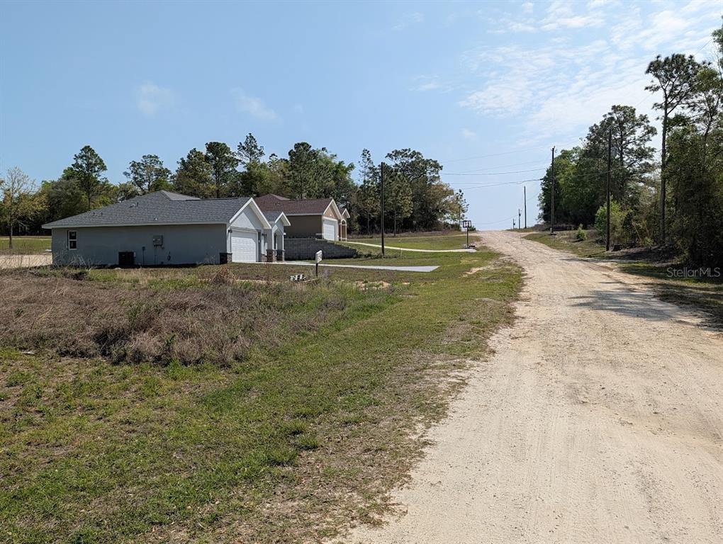 A dirt road leads past a modern single-story house with a garage and driveway — SW 30TH PLACE, OCALA, FL