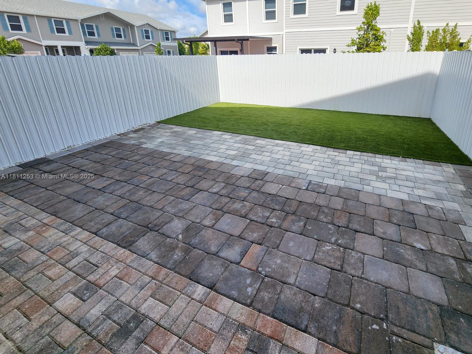 The exterior of a two-story gray townhouse features a front-facing garage and paved driveway — 907 SE 17th Ct, Homestead FL 33034, HOMESTEAD, FL