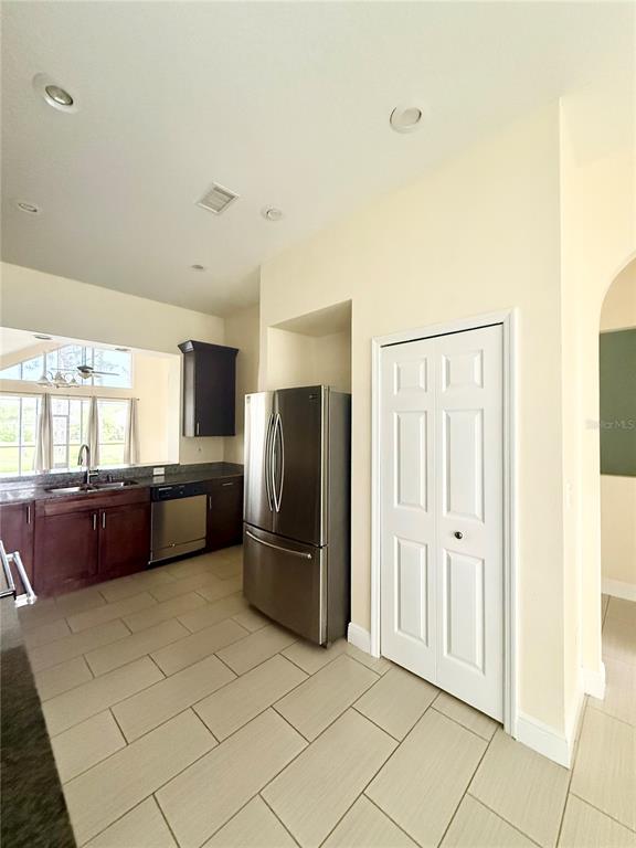 A kitchen features dark wood cabinets, stainless steel appliances, and light-colored tile flooring — 4349 CRYSTAL DOWNS COURT, WESLEY CHAPEL, FL