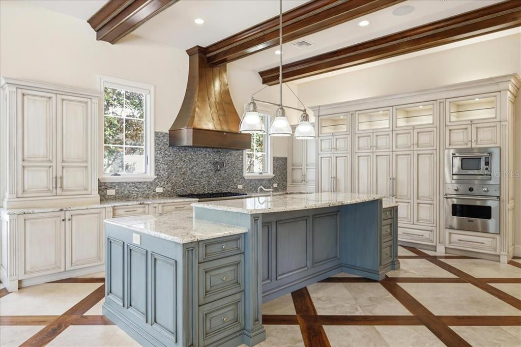 A kitchen with a blue island, white cabinetry, granite countertops, and exposed wooden ceiling beams — 4906 AVIVA GARDEN COURT, WINDERMERE, FL