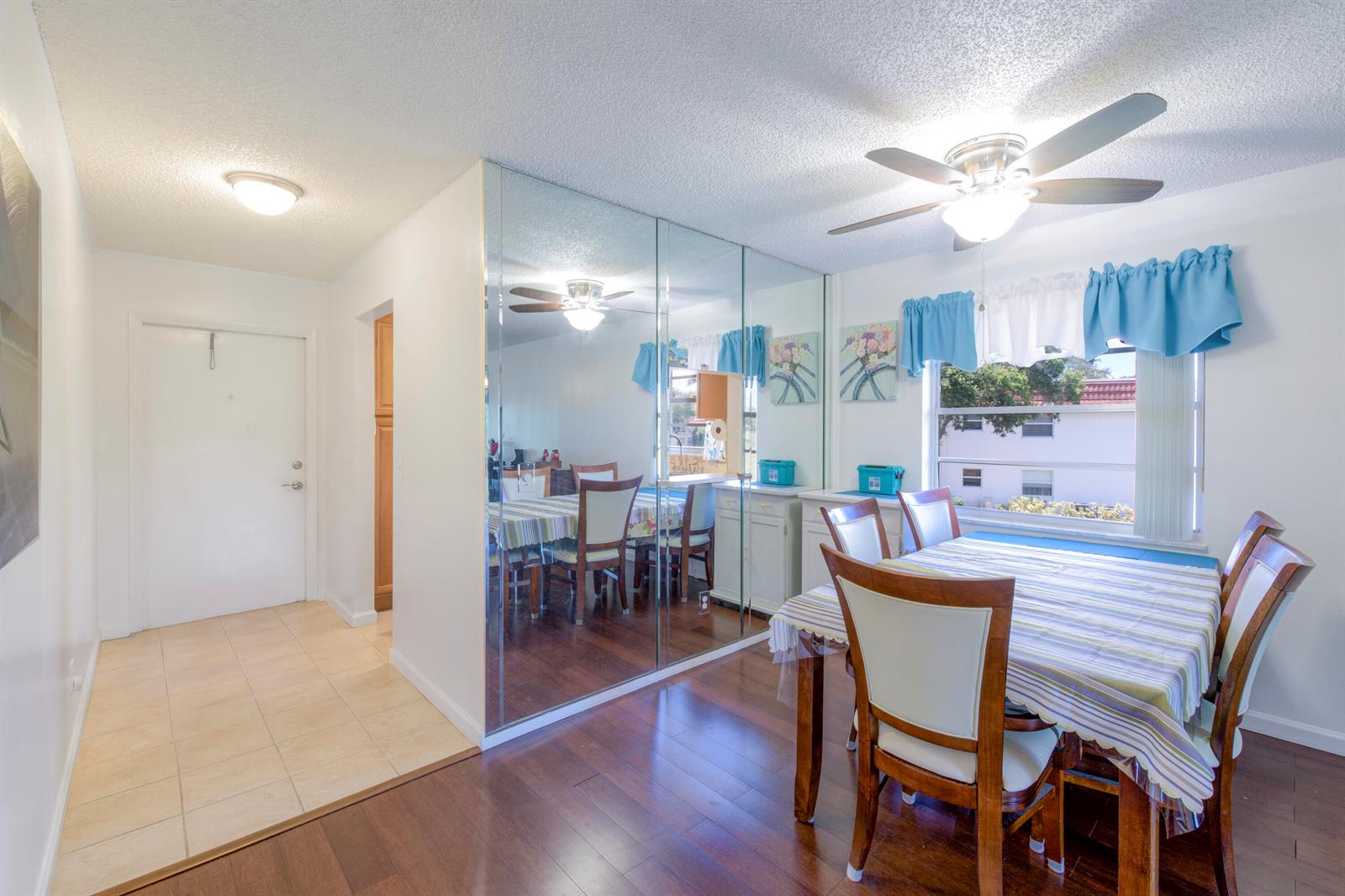 A dining area features a mirrored wall, wood flooring, a ceiling fan, and a window — 1225 NW 21st Street # 1615, Stuart FL 34994, STUART, FL