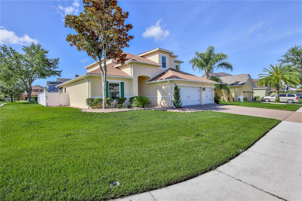 A two-story suburban house with a tan stucco exterior, a two-car garage, and a lawn — 13772 DUNWOODY DRIVE, SPRING HILL, FL