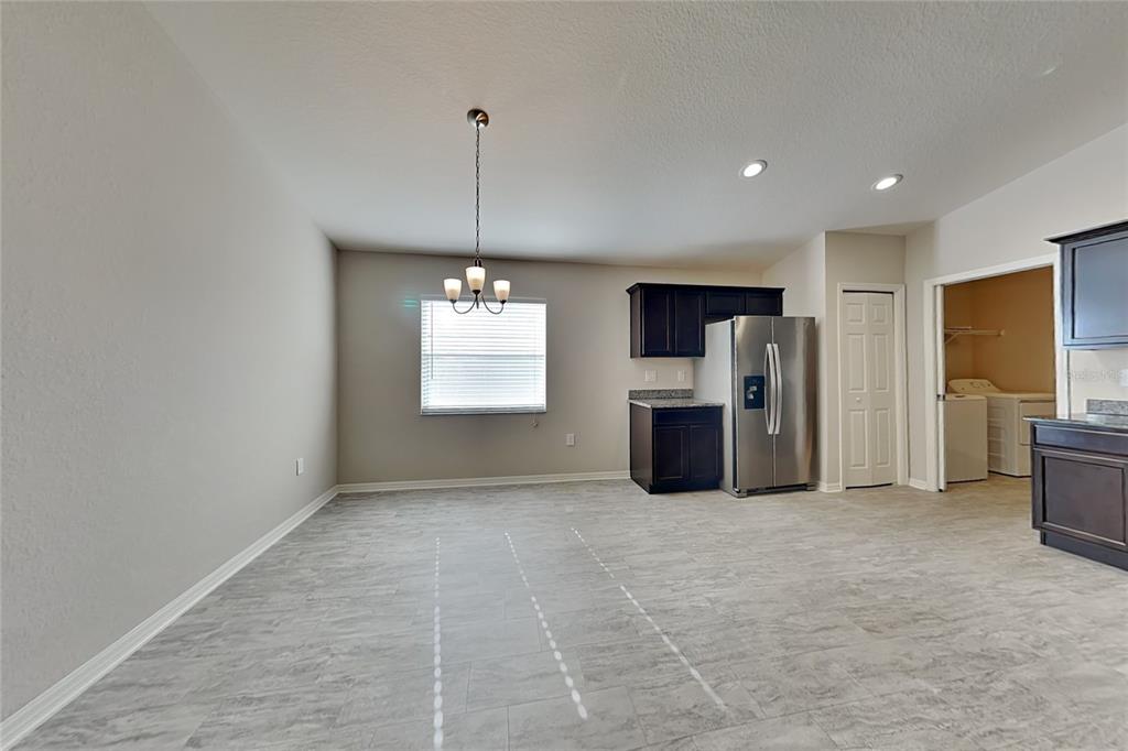 A dining area with gray tile flooring, a chandelier, and an adjacent kitchen with stainless appliances — 505 INTERLOCK STREET, LAKE ALFRED, FL