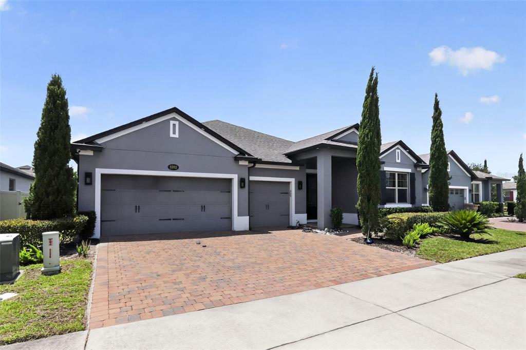 A gray single-story house with a three-car garage and a paved driveway — 5352 COSTA DEL SOL DRIVE, ST CLOUD, FL