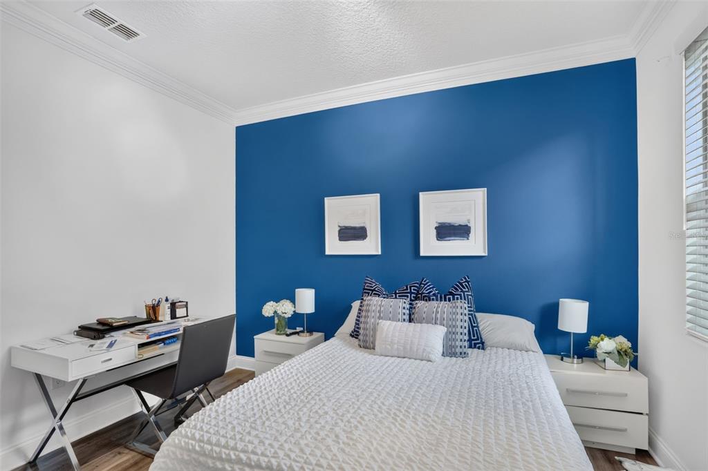 A bedroom features a blue accent wall, a white bed, two nightstands, and a desk — 5352 COSTA DEL SOL DRIVE, ST CLOUD, FL