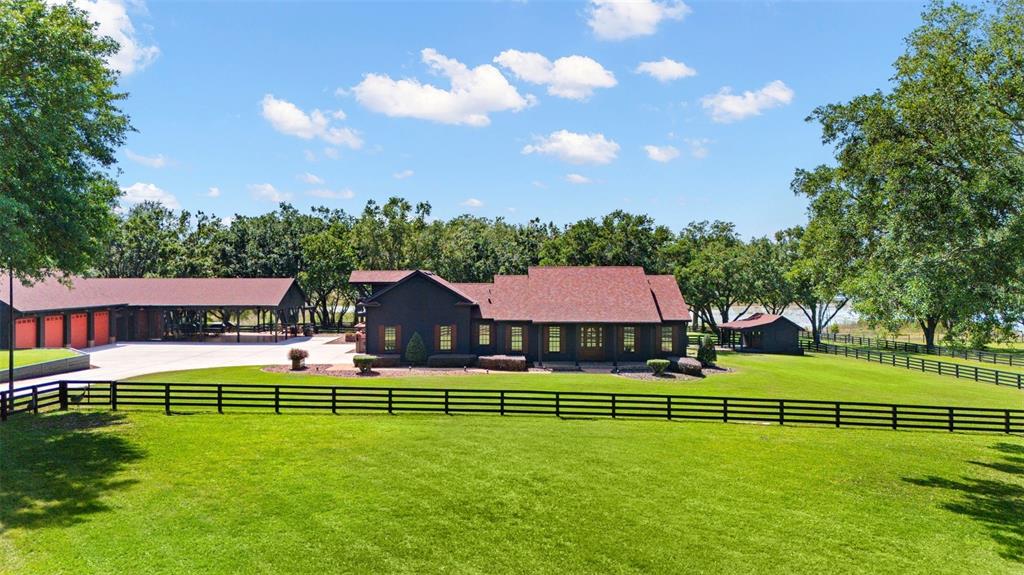 A dark-colored house with a red roof sits behind a black fence on a lawn — 9751 QUIET LANE, WINTER GARDEN, FL