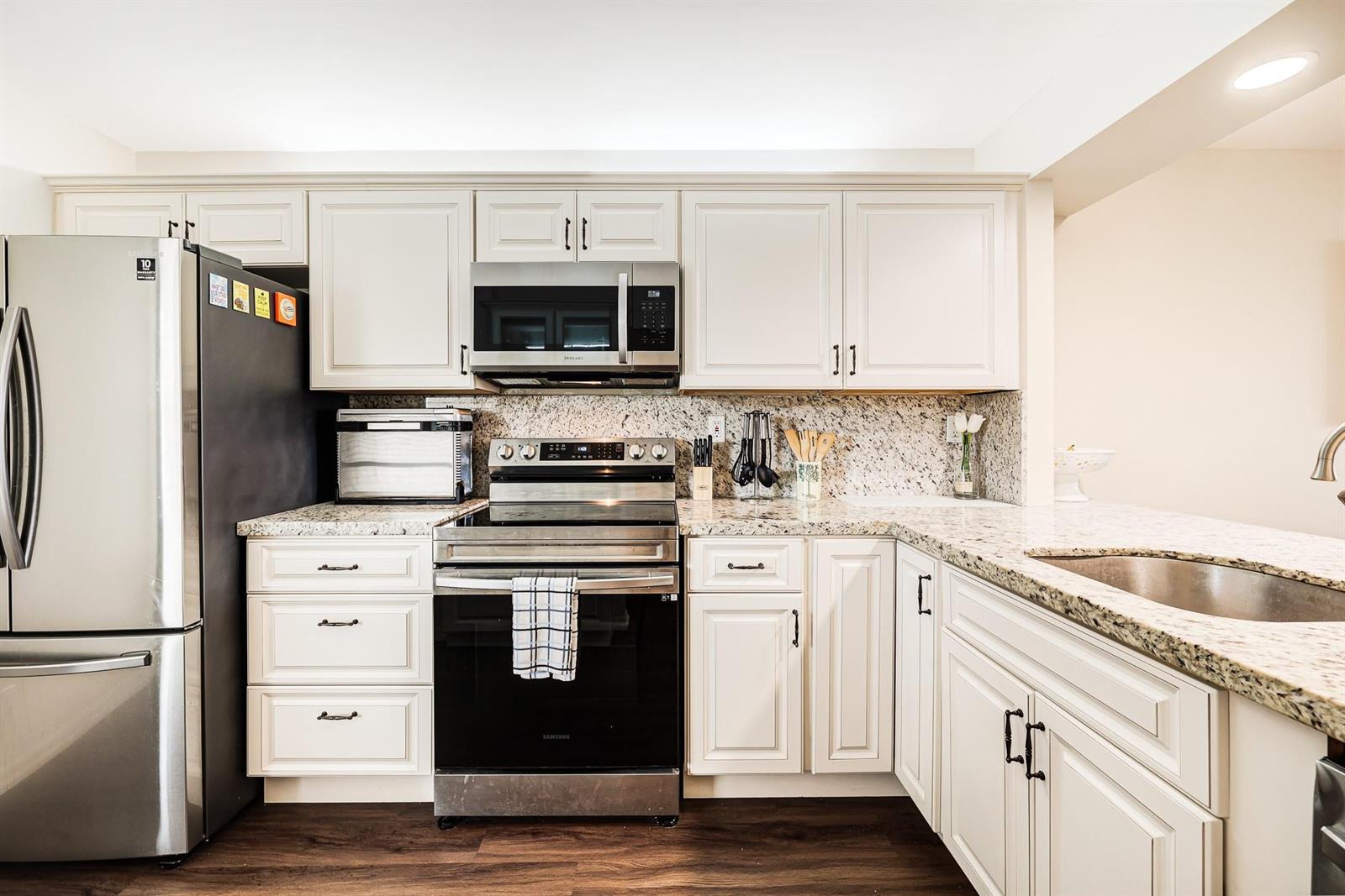 A kitchen with white cabinets, granite countertops, stainless steel appliances, and dark wood flooring — 6 Royal Palm Way # 303, Boca Raton FL 33432, BOCA RATON, FL