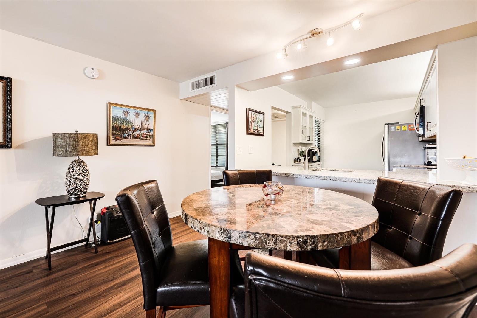 A dining area with a marble-topped table, dark chairs, and an open kitchen view — 6 Royal Palm Way # 303, Boca Raton FL 33432, BOCA RATON, FL