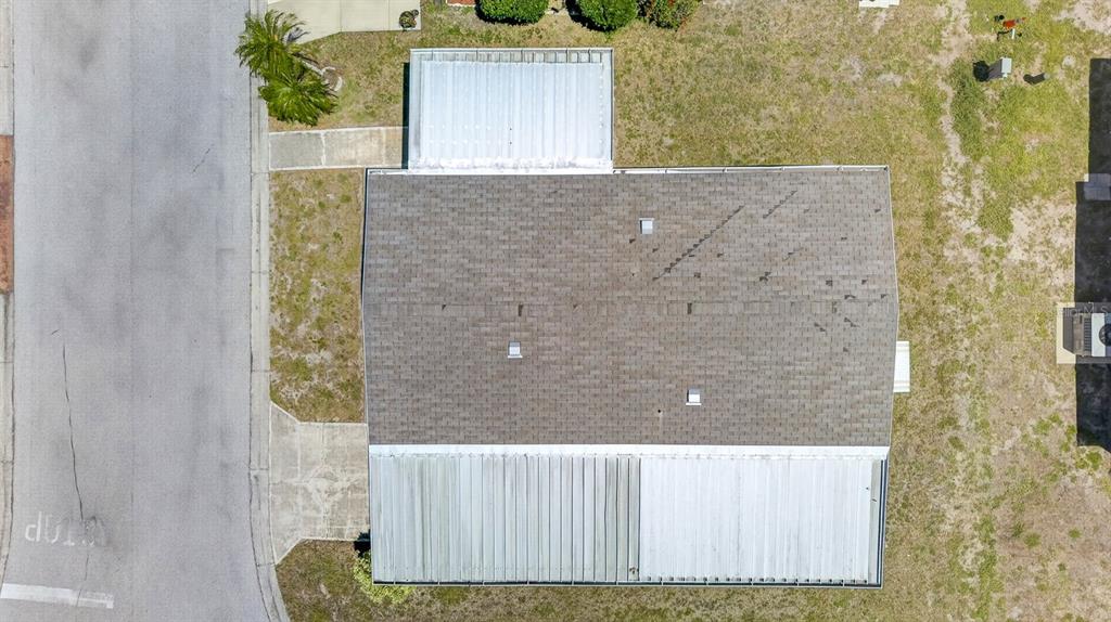 An aerial view shows a house with a shingled roof and two metal-roofed extensions — 8906 31ST AVENUE E, PALMETTO, FL