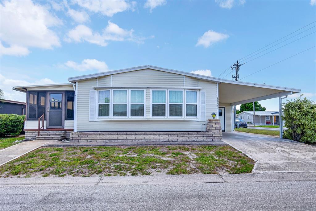 A single-story manufactured home features light siding, a front porch, and an attached carport — 8906 31ST AVENUE E, PALMETTO, FL