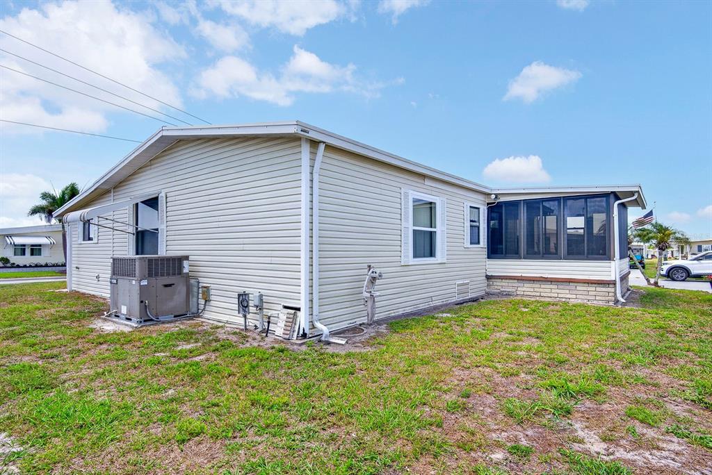 The exterior of a light-colored mobile home features a screened-in porch and an AC unit — 8906 31ST AVENUE E, PALMETTO, FL