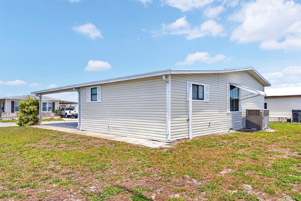 A single-story manufactured home with light-colored siding, a carport, and an outdoor air conditioning unit — 8906 31ST AVENUE E, PALMETTO, FL