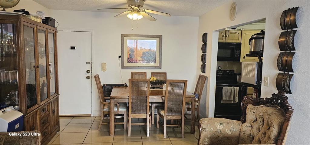 A dining room features a wooden table with six chairs, a hutch, and tiled floors — 6831 W 14 COURT UNIT 306, HIALEAH, FL