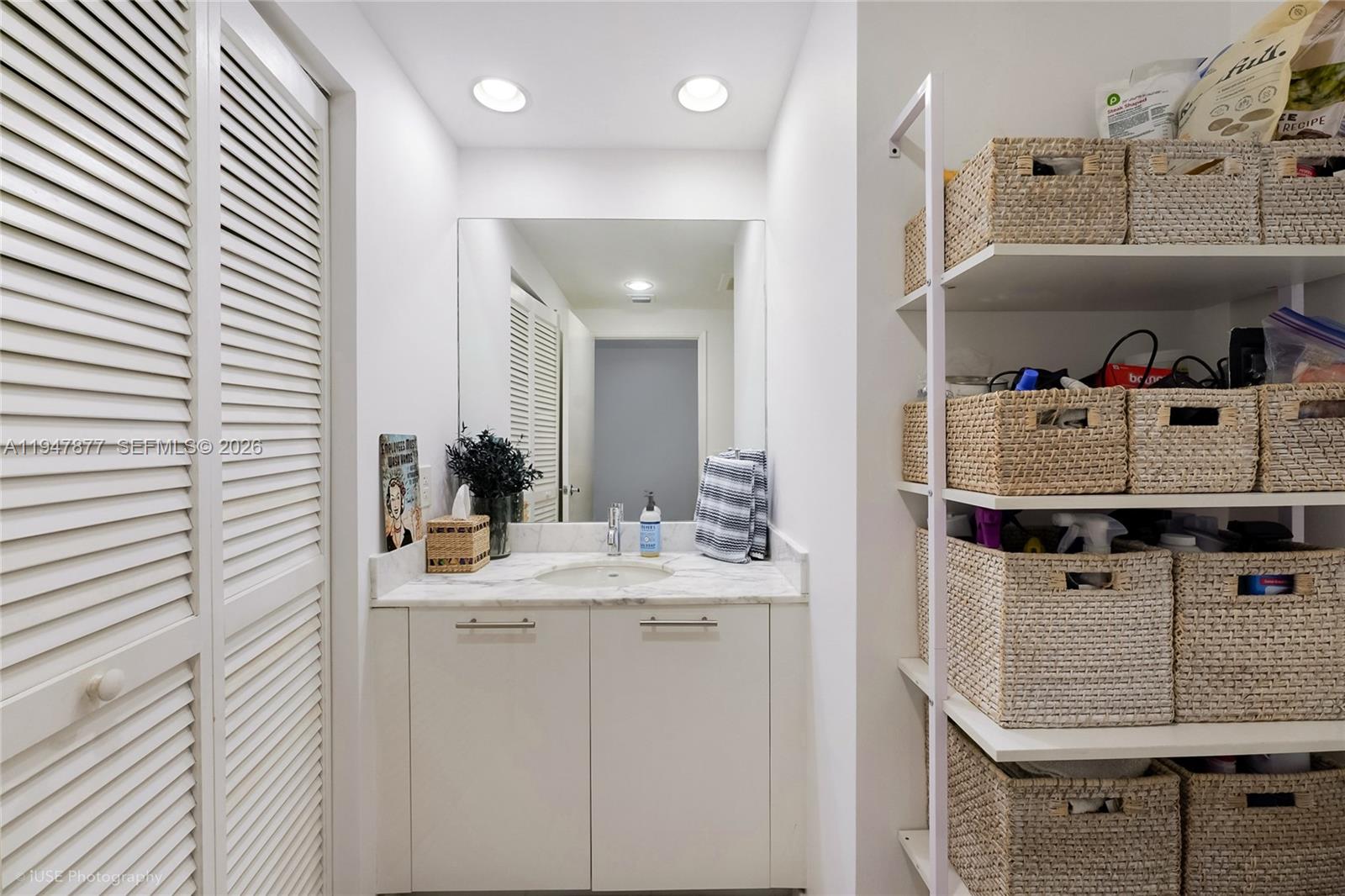 A bathroom vanity with a marble countertop sits next to a white shelving unit — 951 Brickell Ave # 1110, Miami FL 33131, MIAMI, FL