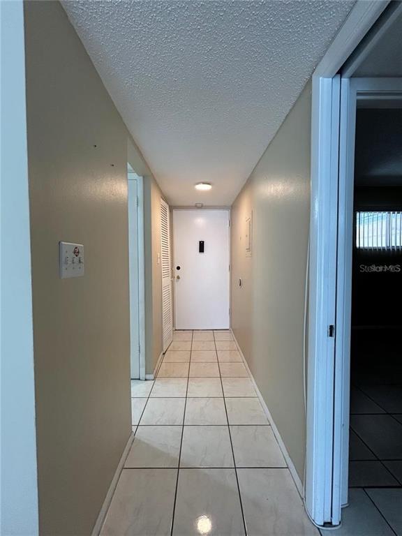 A hallway with light-colored tile flooring leads to a white front door — 2763 WOODGATE LANE UNIT 211, SARASOTA, FL