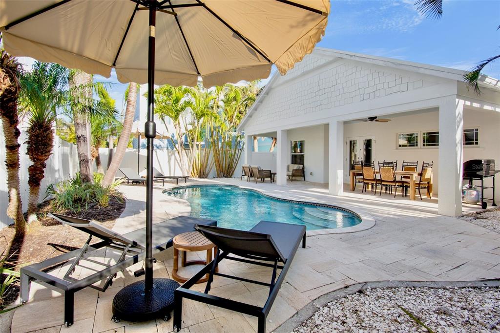 A backyard patio features a swimming pool, lounge chairs, an umbrella, and a covered dining area — 709 FERN STREET, ANNA MARIA, FL