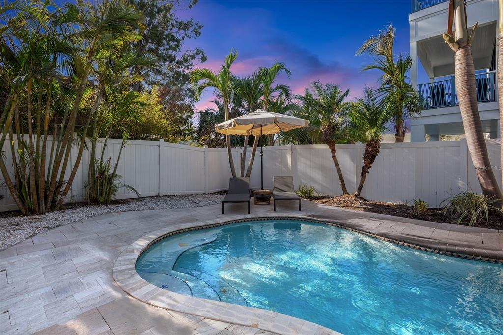 A backyard swimming pool with lounge chairs and an umbrella surrounded by a white fence — 709 FERN STREET, ANNA MARIA, FL