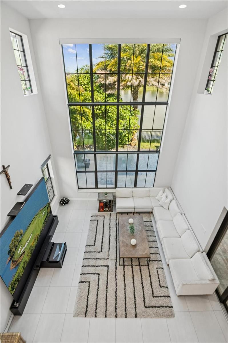 A high-ceiling living room features white tile floors, a large sectional, and floor-to-ceiling windows — 11515 Horizon Road, Parkland FL 33076, PARKLAND, FL