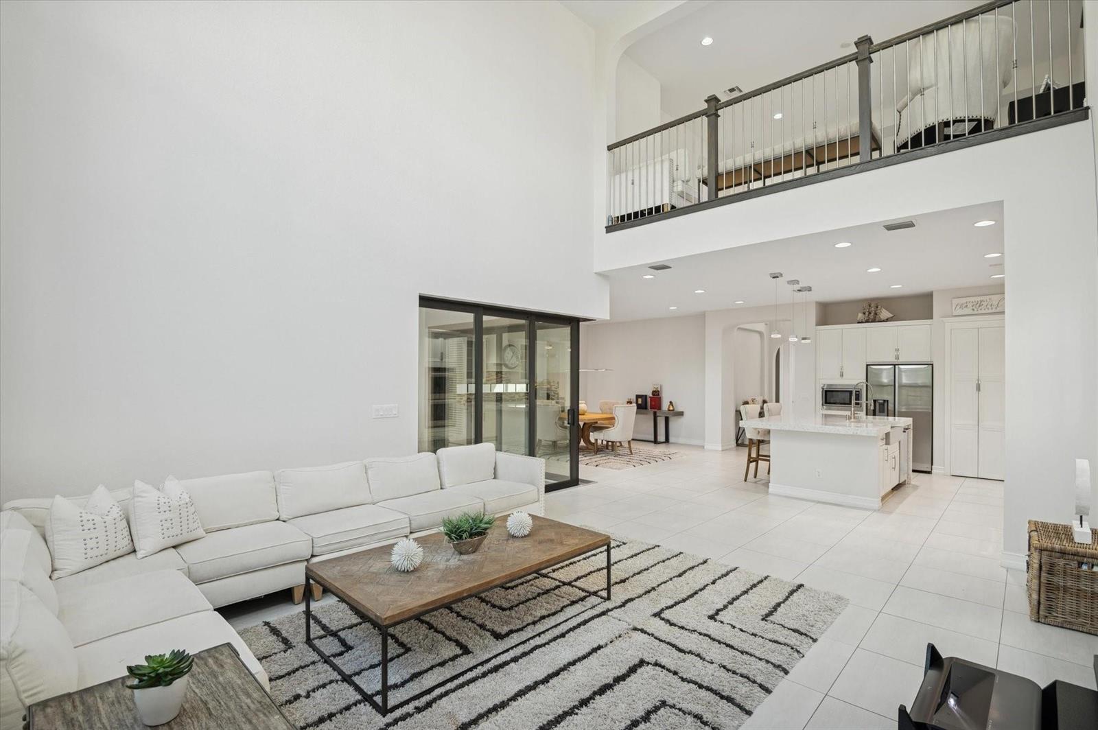 A bright, open-concept living room and kitchen area with high ceilings and white tile floors — 11515 Horizon Road, Parkland FL 33076, PARKLAND, FL