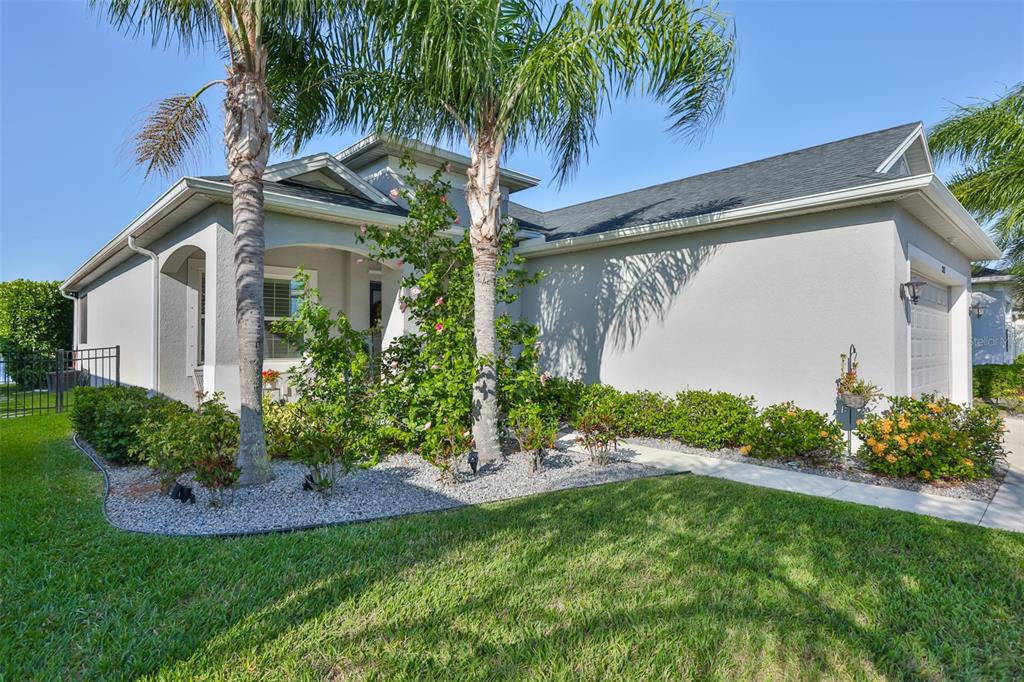 A single-story house with a gray stucco exterior, a palm tree, and a landscaped yard — 12421 GLENRIDGE LANE, PARRISH, FL