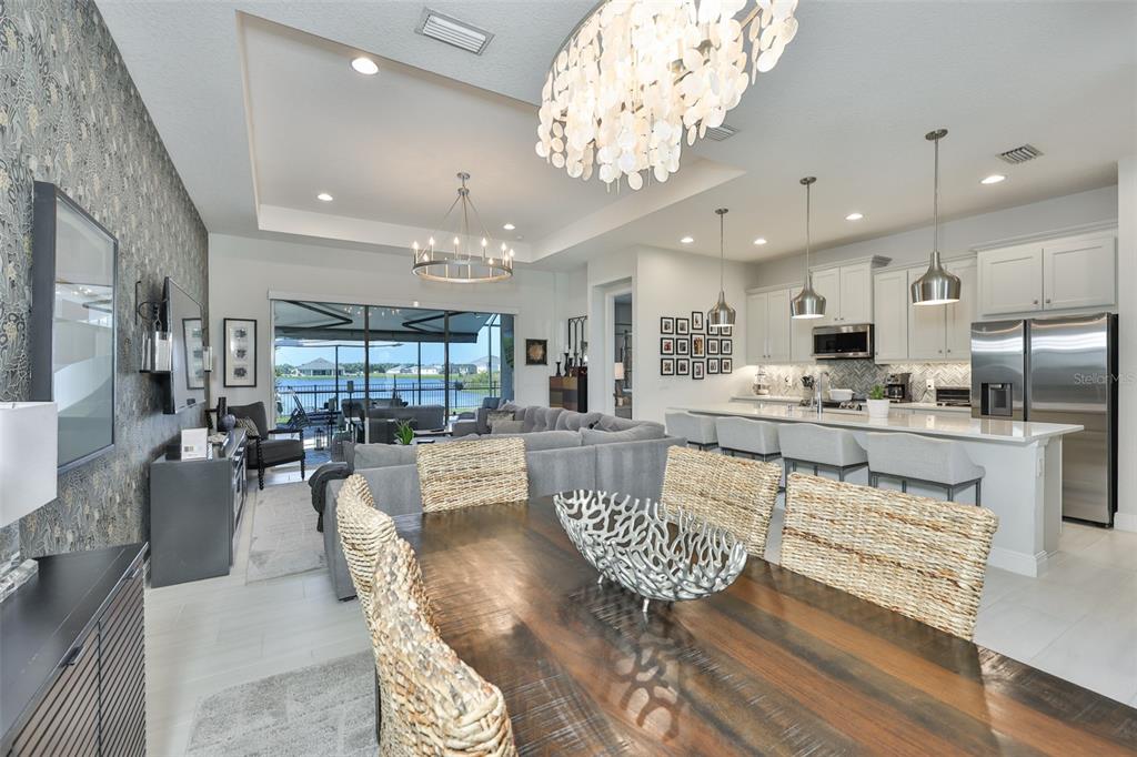 An open-concept dining area and kitchen feature a wooden table, chandelier, and lake view — 12421 GLENRIDGE LANE, PARRISH, FL
