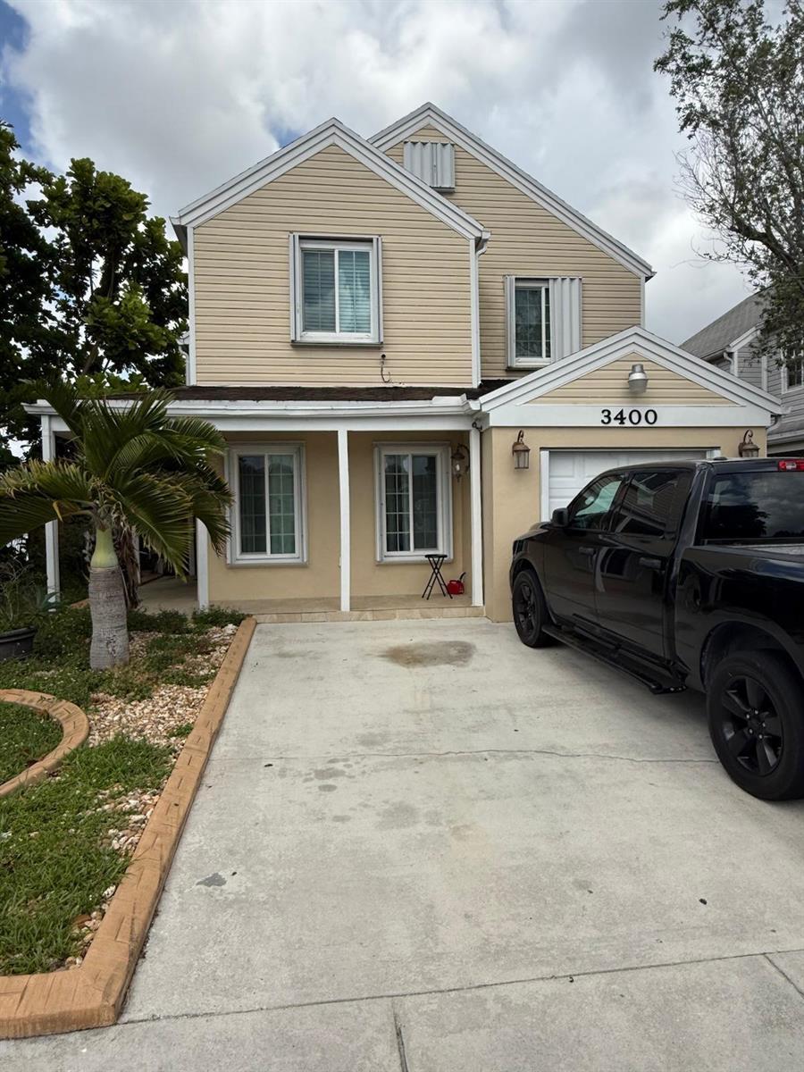 A two-story house with tan siding, a concrete driveway, and a black pickup truck parked outside — 3400 Ivy Way, Miramar FL 33025, MIRAMAR, FL