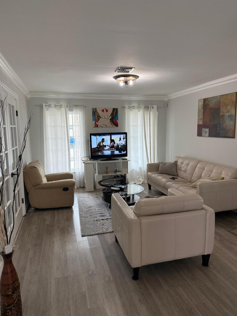 A living room with light wood-look flooring, a beige sofa, a recliner, and a television — 3400 Ivy Way, Miramar FL 33025, MIRAMAR, FL