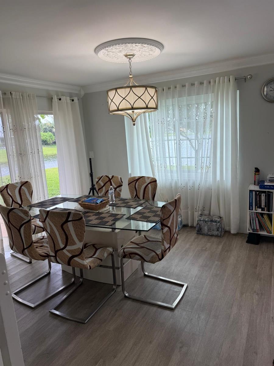 A dining room features a glass-top table, patterned chairs, a chandelier, and floor-to-ceiling curtains — 3400 Ivy Way, Miramar FL 33025, MIRAMAR, FL